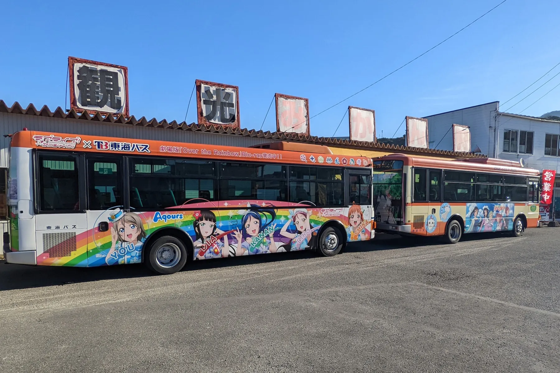 東海バスのラブライブ！サンシャイン!!ラッピングバス 1号車とあまんちゅのラッピングバスが並んで止まっている
